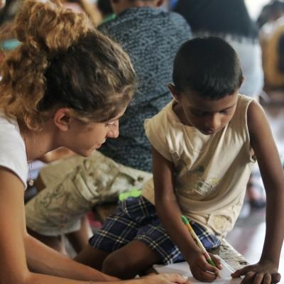 A teenager works on English exercises while volunteering with children in Sri Lanka through Projects Abroad A volunteer works with children on English exercises in Sri Lanka on our project for high school students